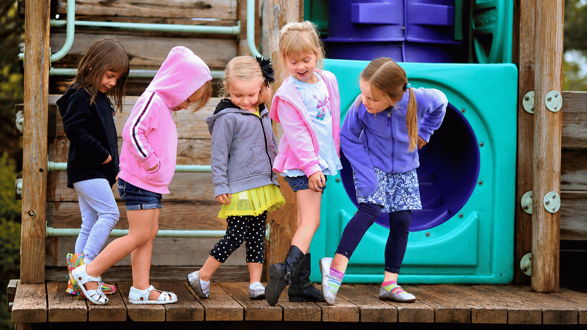 Five school-age girls playing together on the playground climber