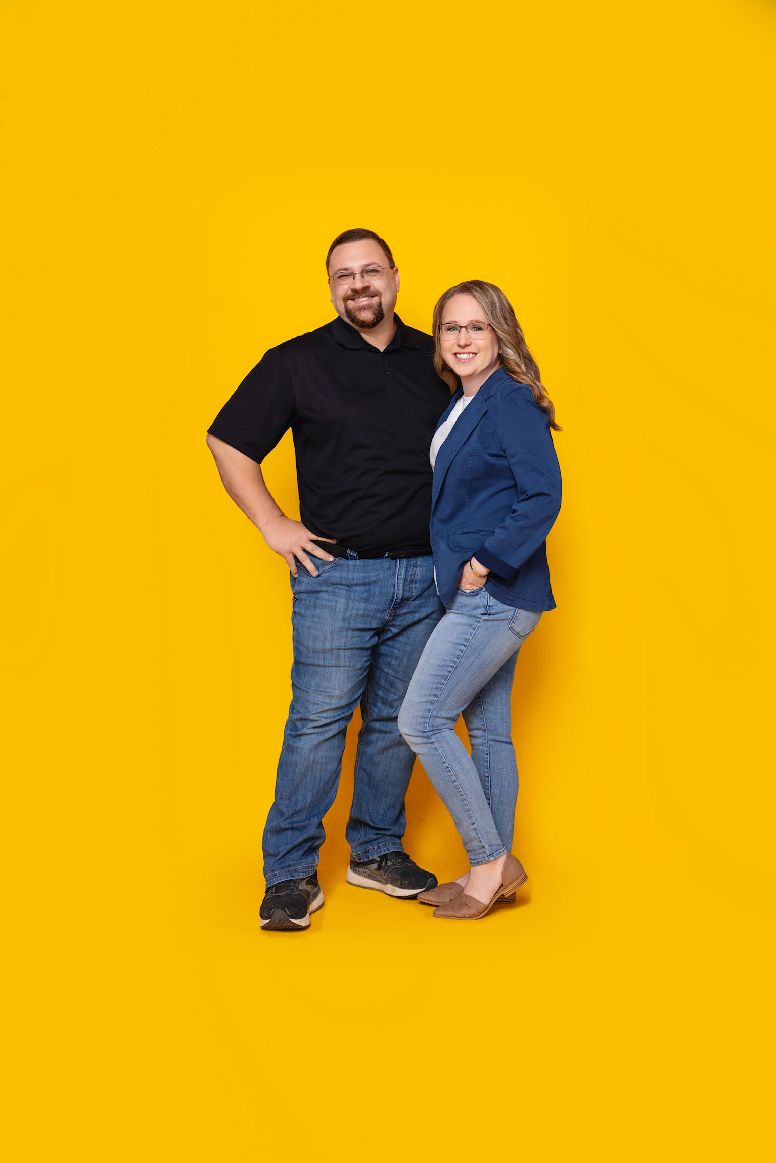 Sara and Greg Schreiner, owners of The Sunshine Academy, standing together against a bright yellow backdrop
